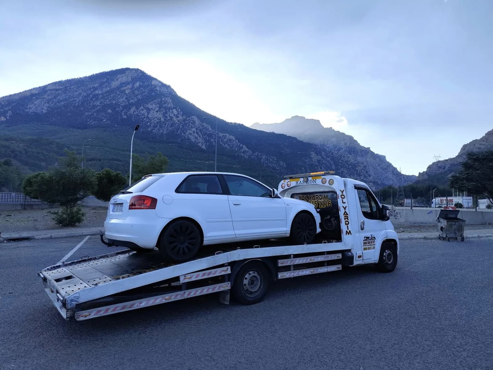 Dağların önünde, beyaz otomobili taşıyan Özerler çekicisi