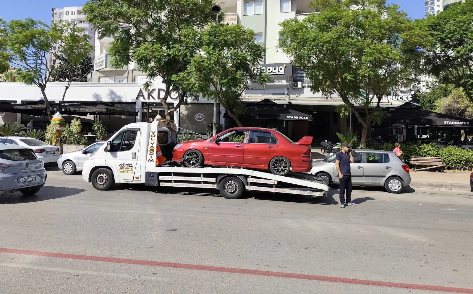 Kırmızı otomobili taşıyan beyaz platformlu çekici